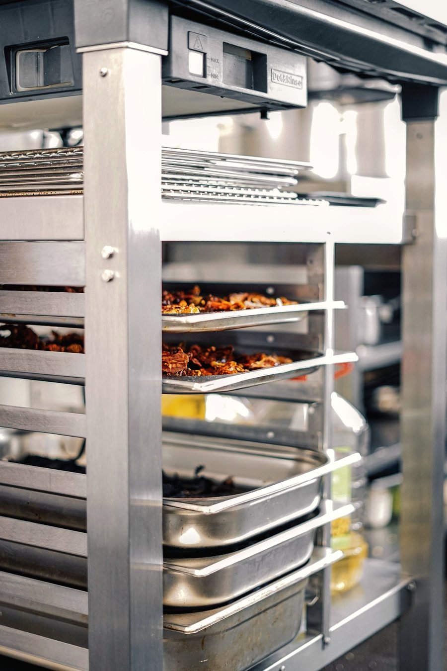 Close view of stainless steel exhaust hood racking and trays in a commercial kitchen.